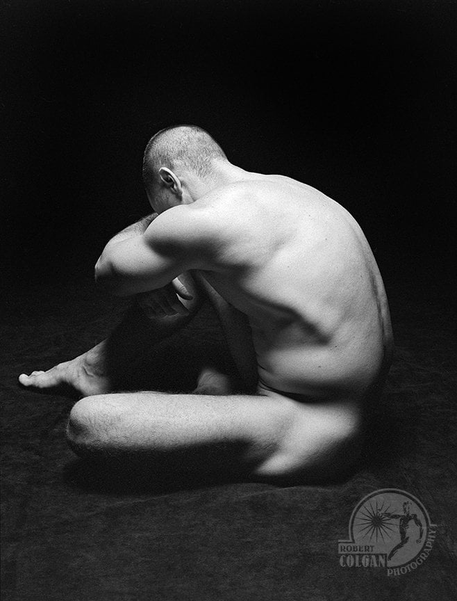 partially visible nude man in darkened studio