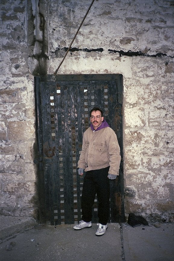 the photographer standing in front of iron doors in old prison