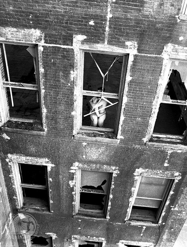 looking down on abandoned building, two nude figures in embrace in window