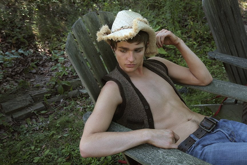 man with straw hat lounging in old wooden chair