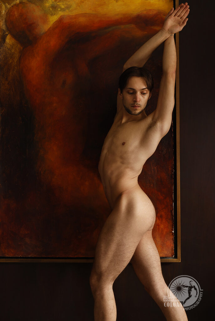 nude man stretches in front of painting of nude figure