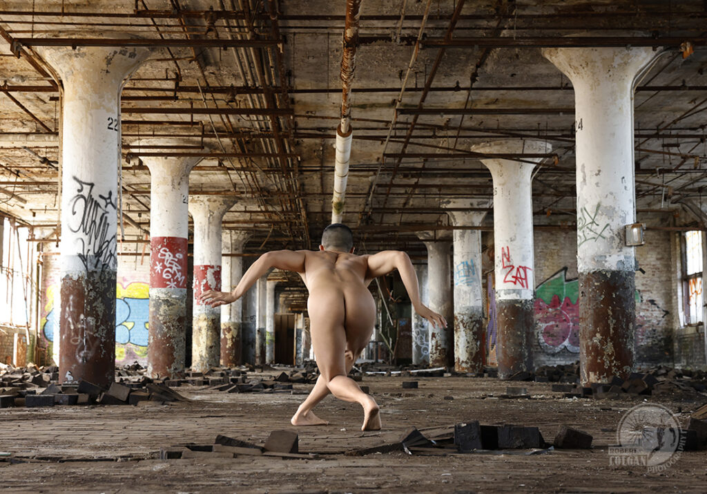 nude man in dance pose in old factory