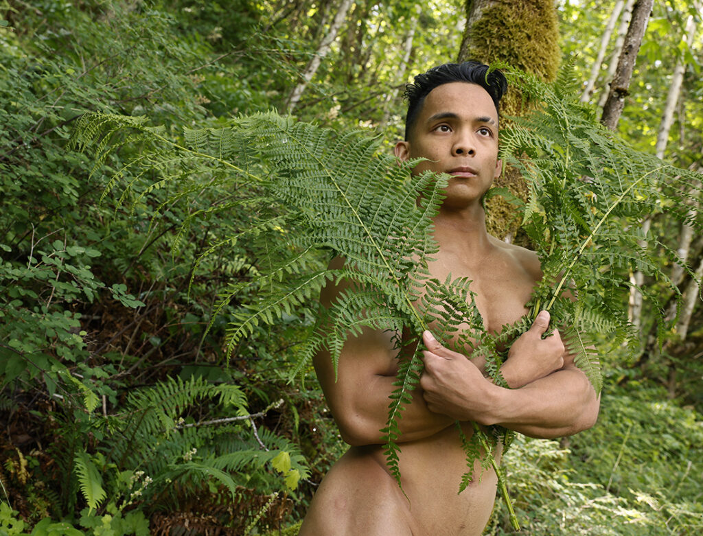 nude man holding ferns across his body