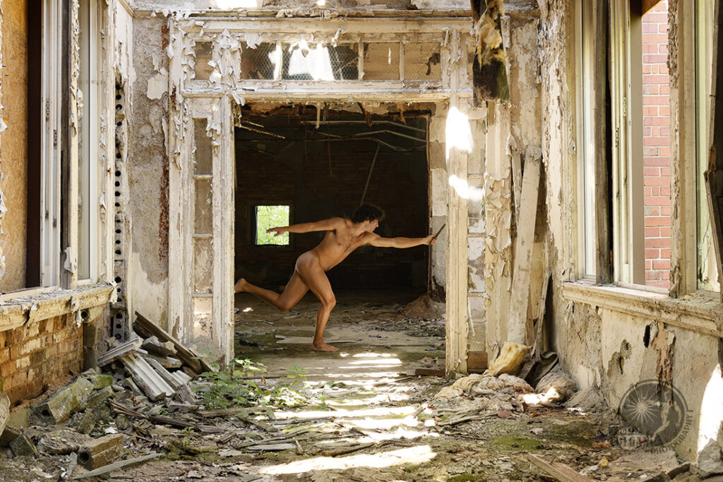 nude man in a running pose at the end of a destroyed hallway